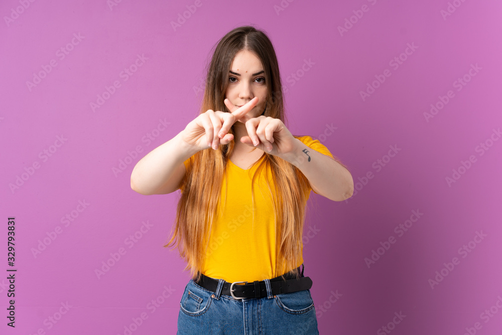 Young caucasian woman isolated on purple background making stop gesture with her hand to stop an act Young caucasian woman isolated on purple background making stop gesture with her hand to stop an act