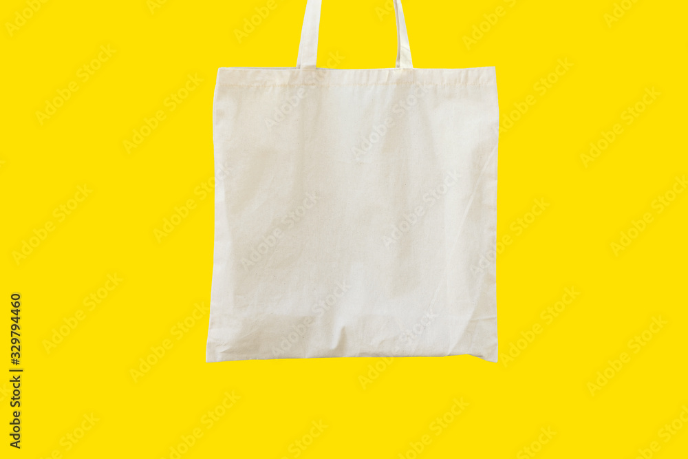 Blank cotton shite shopper tote bag on yellow background. Mock up template for product branding plastic free reusable nature-friendly materials concept Blank cotton shite shopper tote bag on yellow background. Mock up template for product branding plastic free reusable nature-friendly materials concept