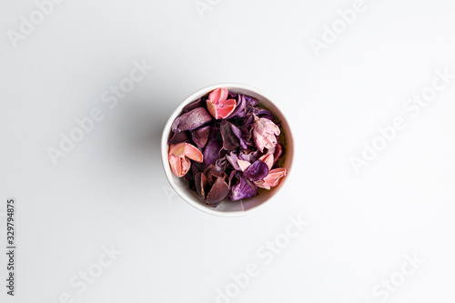 Paper cup of purple and pink dry flowers, branches, leaves and petals on white background. Colorful background image. Top view. Flat lay. Copy space. Art concept. Color trends 2020