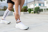 Close Up on Ankle Injury. The man use hands hold on his ankle while running in the park. space for text or design.