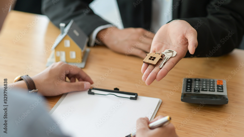 Cropped shot of signing a home purchase contract while the broker holds the house key. Cropped shot of signing a home purchase contract while the broker holds the house key.