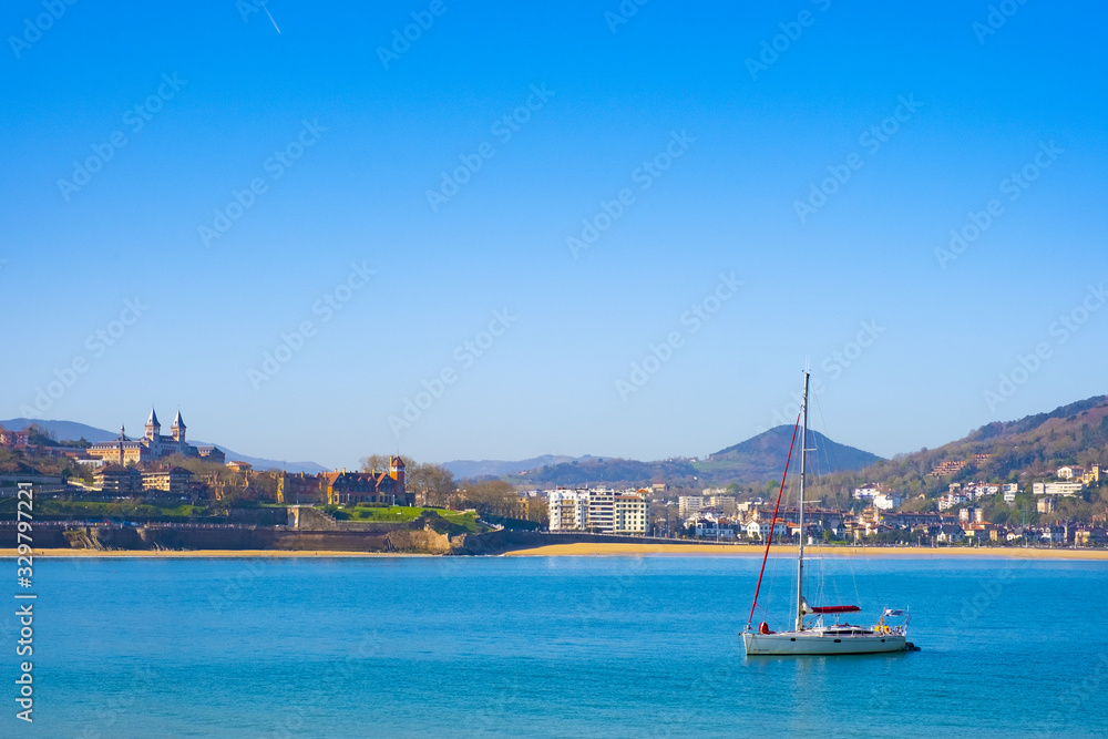 Sailboat docked in La Concha bay, in front of the city of Donostia, Euskadi, Spain