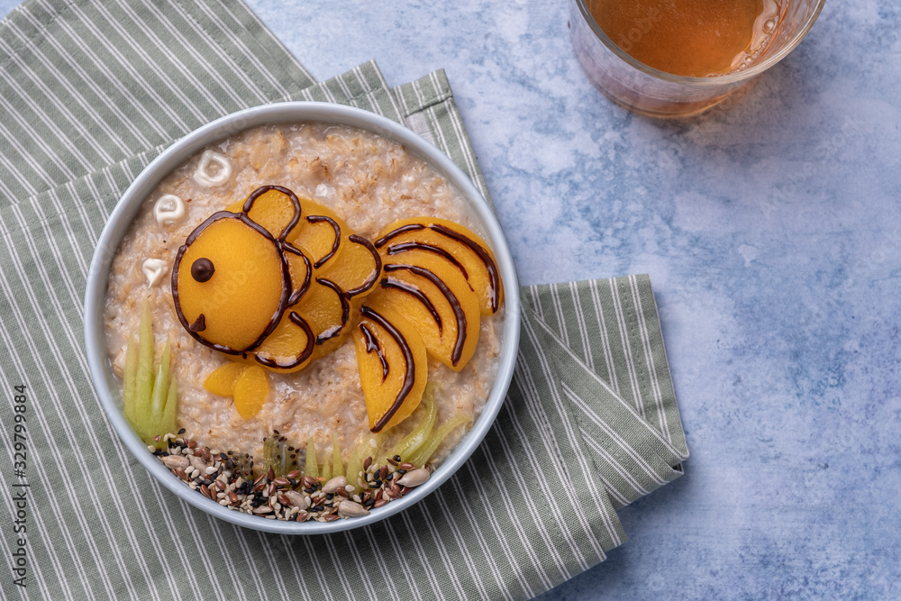 Kids breakfast oatmeal porridge with fruit look like a golden fish Kids breakfast oatmeal porridge with fruit look like a golden fish