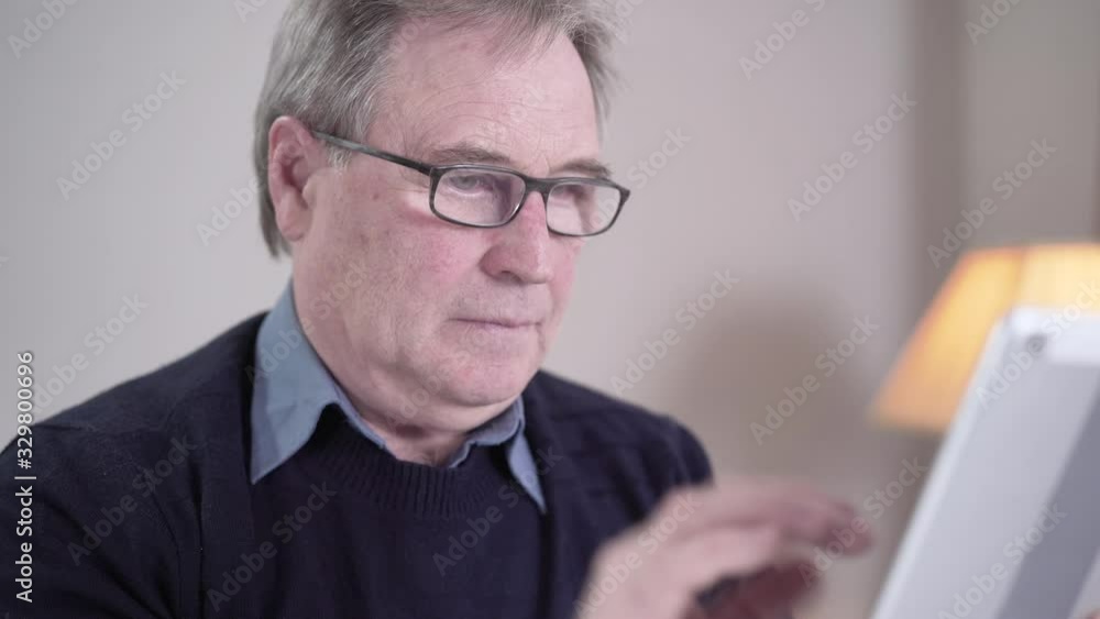 Close-up of tired Caucasian old man tapping tablet screen, taking off eyeglasses and rubbing eyes. Exhausted senior retiree having eye pain as surfing Internet indoors. Aging, lifestyle, health care. Close-up of tired Caucasian old man tapping tablet screen, taking off eyeglasses and rubbing eyes. Exhausted senior retiree having eye pain as surfing Internet indoors. Aging, lifestyle, health care.