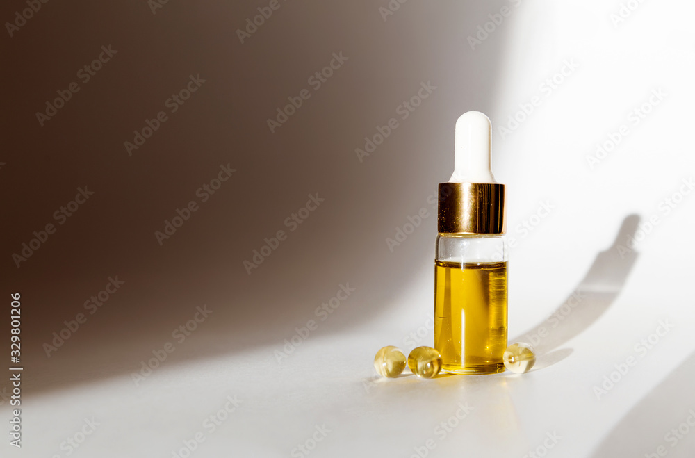 Transparent jar with oil and medical capsules on a white background in the sun. Products CBD