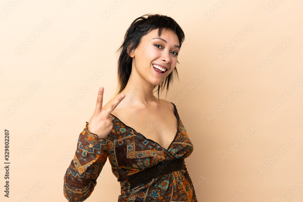 Indian woman isolated on beige background smiling and showing victory sign Indian woman isolated on beige background smiling and showing victory sign