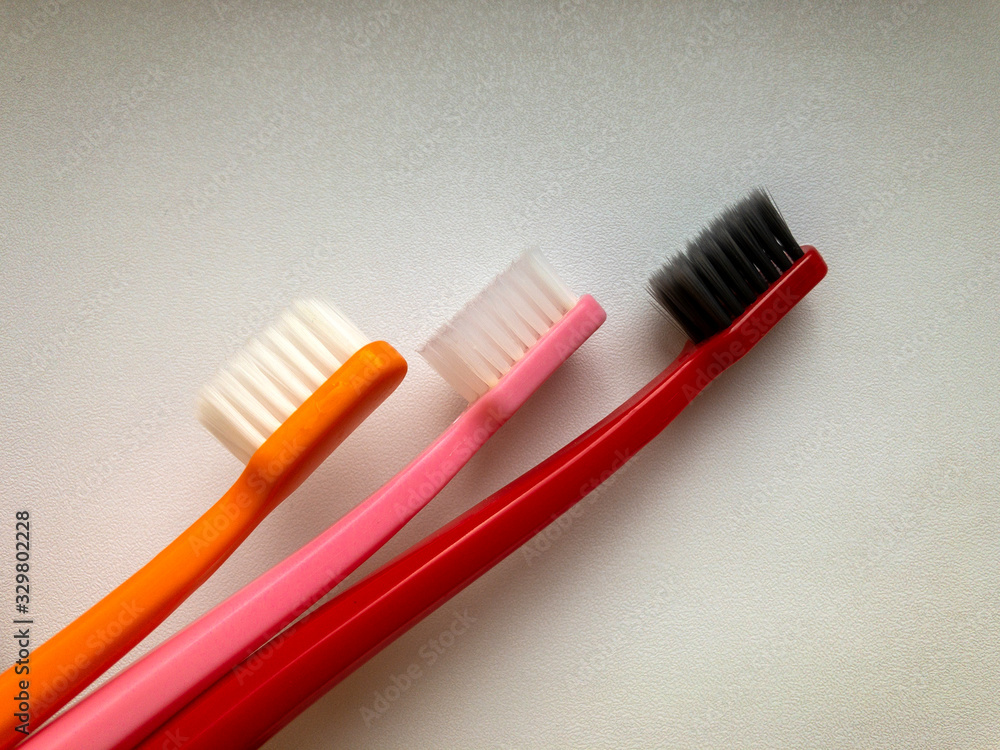 three multi-colored toothbrushes on a white background three multi-colored toothbrushes on a white background