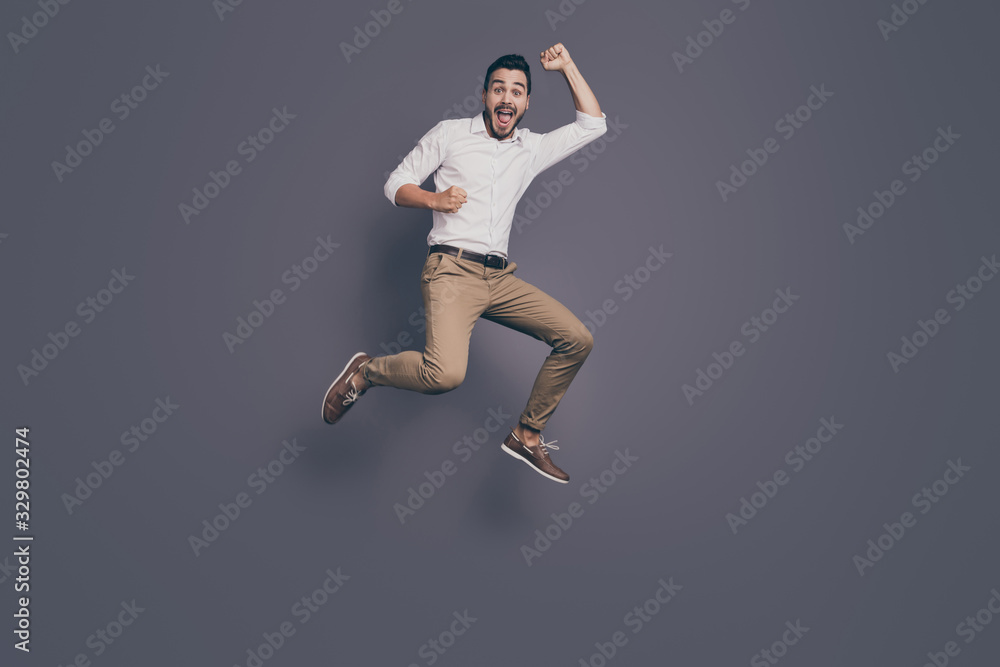 Full length photo of young handsome business man jumping high up rejoicing celebrating new startup project success wear white shirt pants footwear isolated grey color background