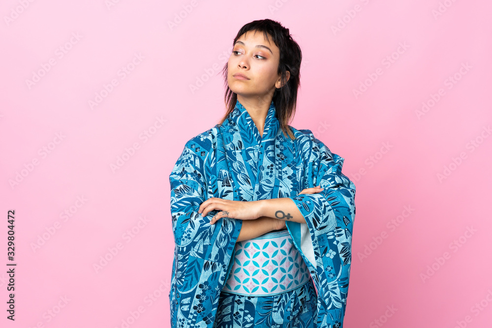 Young woman wearing kimono over isolated blue background keeping the arms crossed Young woman wearing kimono over isolated blue background keeping the arms crossed