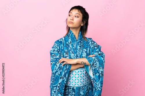 Young woman wearing kimono over isolated blue background keeping the arms crossed