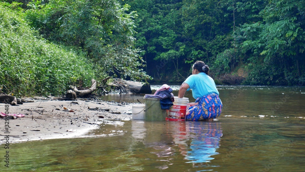 A woman is doing her laundry on the riverbank at Gunung Mulu Nationalpark, Borneo