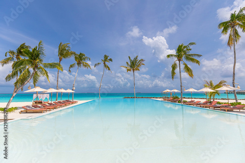 Fototapeta Naklejka Na Ścianę i Meble -  Amazing infinity pool and beautiful nature. Luxury hotel resort beach landscape, summer vacation or holiday concept. Sea bay, palm trees, loungers and umbrellas with swimming pool. Luxury travel