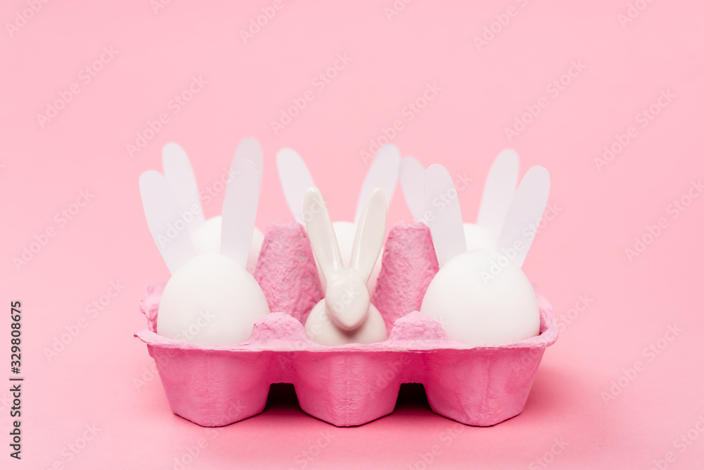 Easter rabbits in egg tray on pink background Easter rabbits in egg tray on pink background