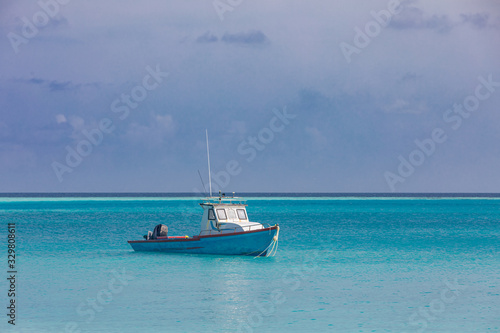 Small fishing boat and ship in front of beautiful seascape scenery and blue sky at Maldives island. Traditional and way of life concept.