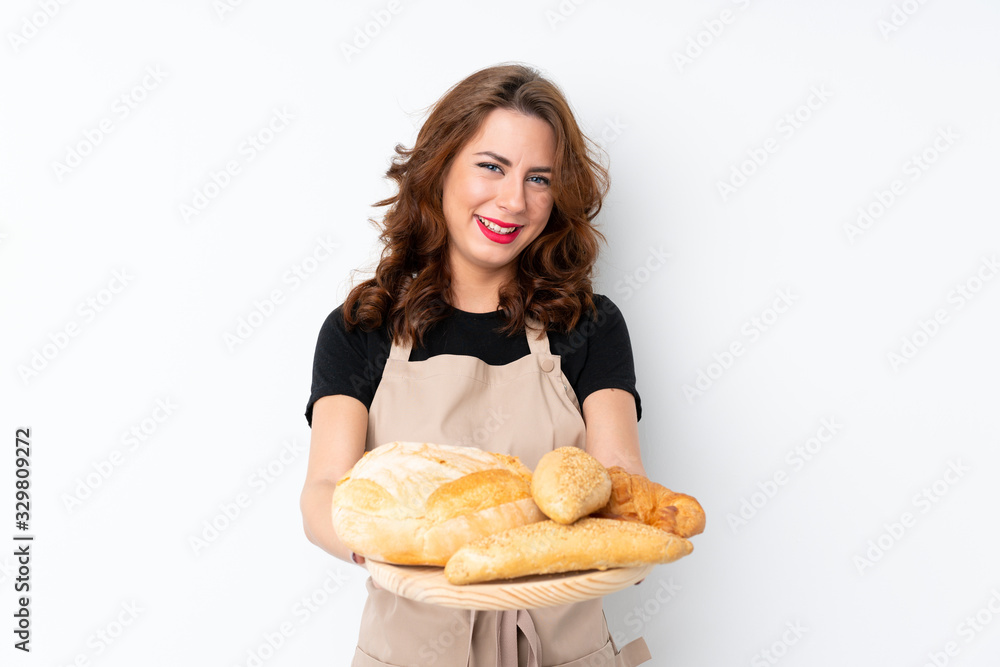 Woman in chef uniform. Female baker holding a table with several breads with happy expression Woman in chef uniform. Female baker holding a table with several breads with happy expression