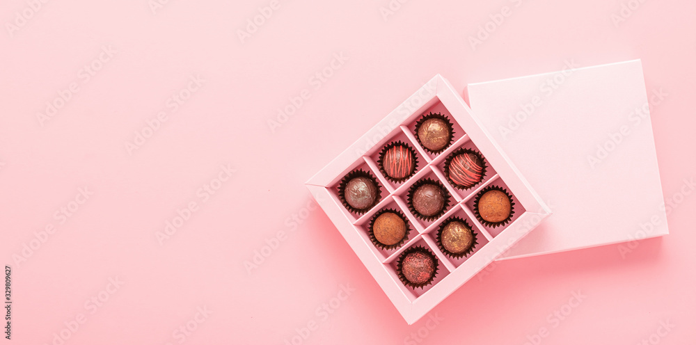 Chocolate truffle candies in a box pink background. Gifts festive food love concept. Horizontal frame copy space Chocolate truffle candies in a box pink background. Gifts festive food love concept. Horizontal frame copy space