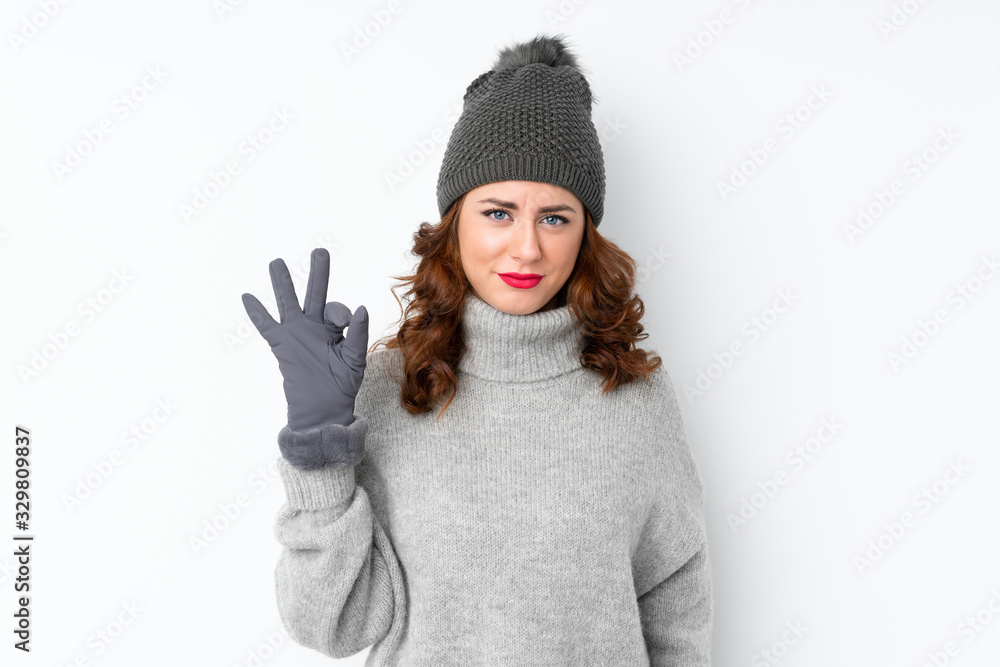 Young Russian woman with winter hat over isolated white background showing an ok sign with fingers Young Russian woman with winter hat over isolated white background showing an ok sign with fingers