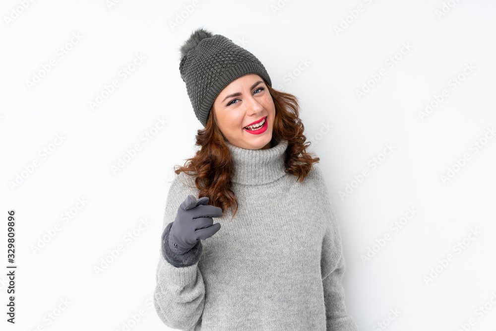 Young Russian woman with winter hat over isolated white background points finger at you Young Russian woman with winter hat over isolated white background points finger at you