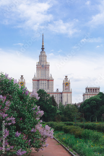Fresh pink and purple lilac bushes background of Moscow State University, copyspace, selective focus, toned