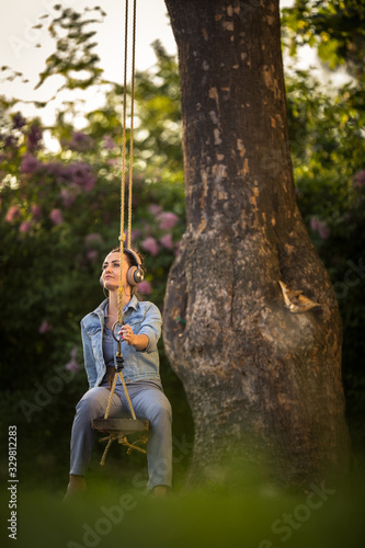 Pretty, young woman with headphones outdoors, in a lovely park, enjoyig the hi-fi quality sound, listening to her favorite songs (color toned image) photo