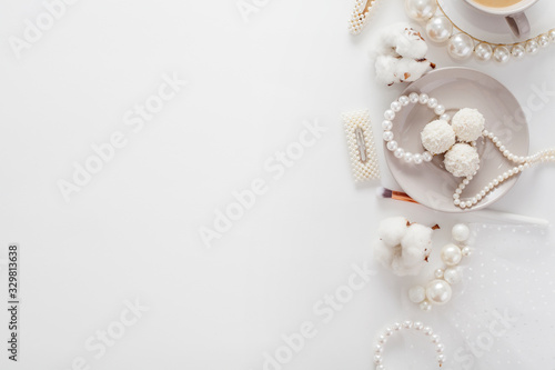 Wedding composition top view, decorated with pearl jewelry, coconut candy, cotton flower, coffee, hairpins, makeup brush, all in pastel soft colors. Concept morning of the bride.