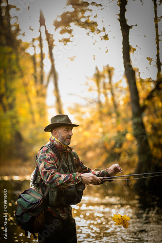 Handsome fisherman holding a lovely trout while fly fishing on a splendid mountain river