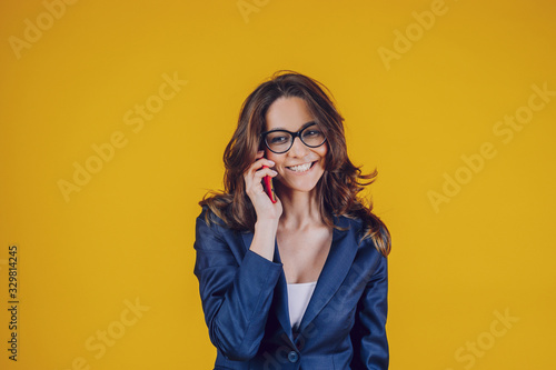 The elegantly dressed European woman, holds the phone to her ear and speaks to someone, feels distracted and satisfied, has a beautiful smile.