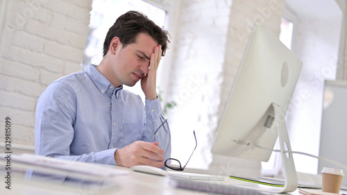 Tired Working Young Man having Headache in Modern Office
