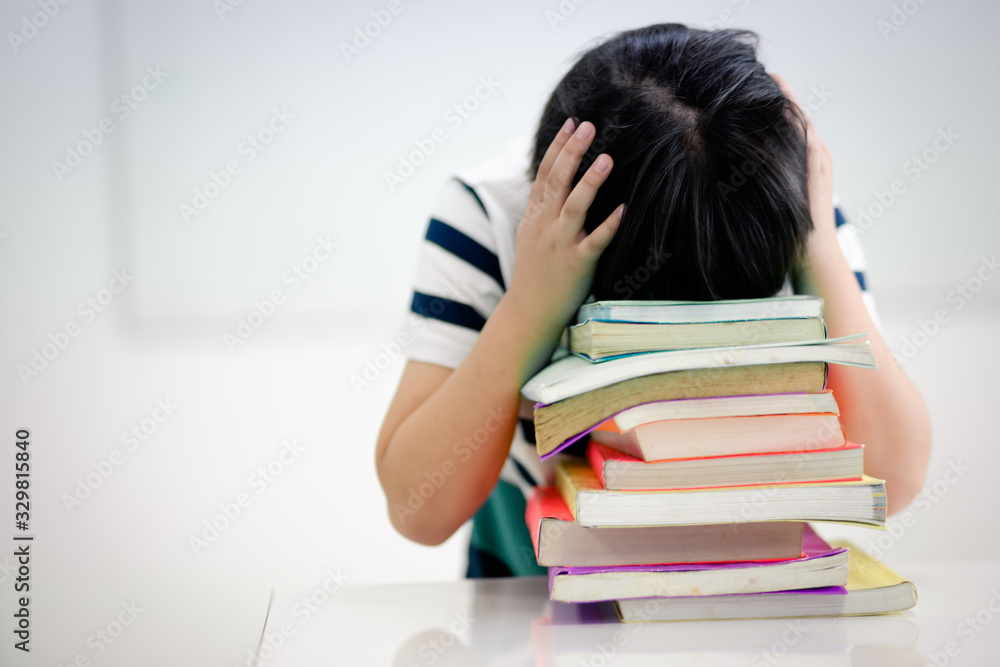 Boy student Sitting in a head in the library Headache with reading exam During the final exam of the school. Boy student Sitting in a head in the library Headache with reading exam During the final exam of the school.