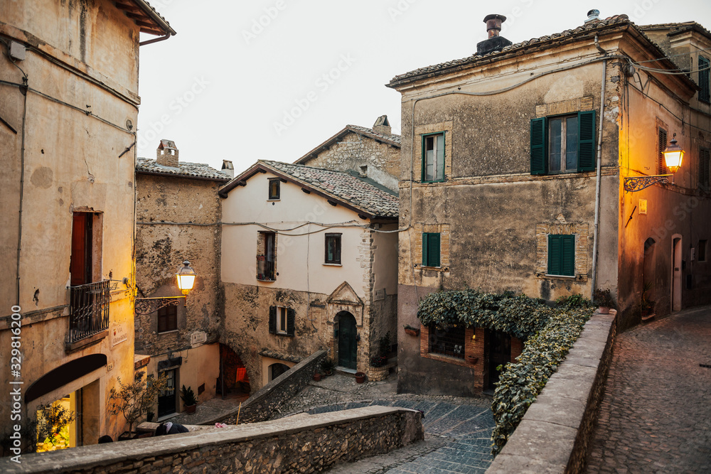 Beautiful view of old traditional houses and idyllic alleyway in the historic town province of Viterbo, Lazio, Italy. A small road among the old houses of a medieval village. Evening time. Nobody.