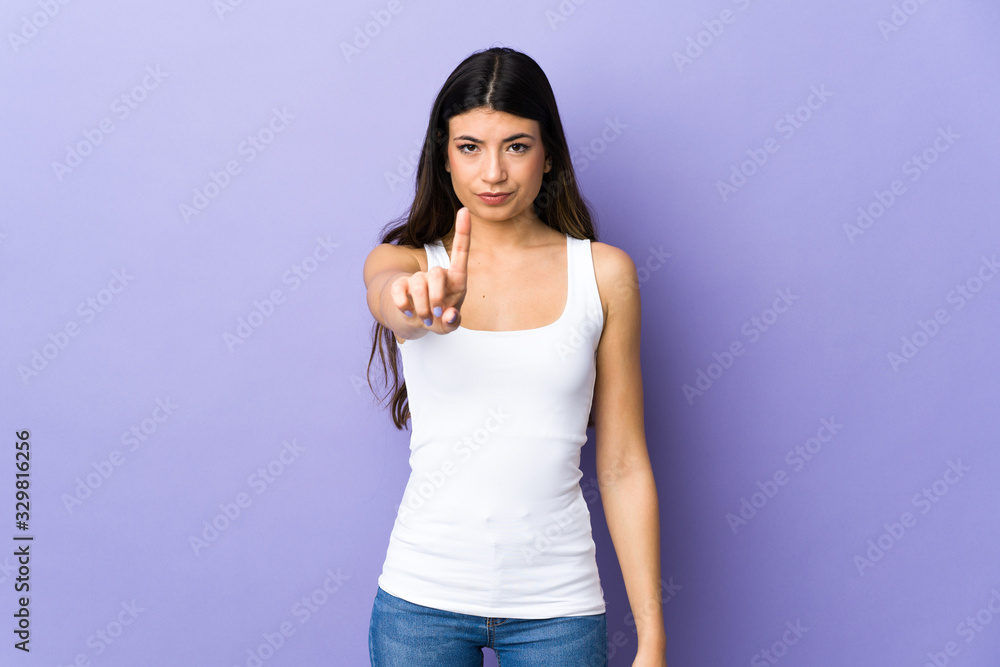Young brunette woman over isolated purple background counting one with serious expression Young brunette woman over isolated purple background counting one with serious expression