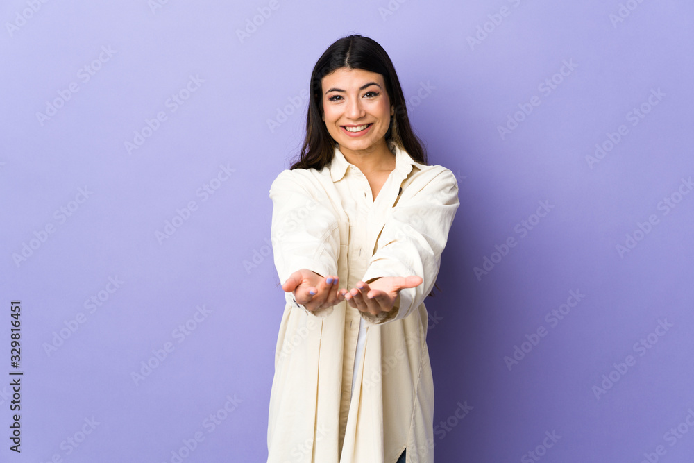 Young brunette woman over isolated purple background holding copyspace imaginary on the palm to insert an ad Young brunette woman over isolated purple background holding copyspace imaginary on the palm to insert an ad
