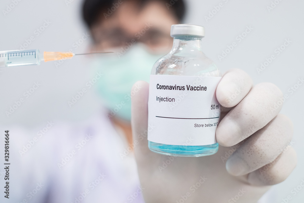 Doctor's hand holding a syringe of covid-19 vaccine and vaccine vial Doctor's hand holding a syringe of covid-19 vaccine and vaccine vial