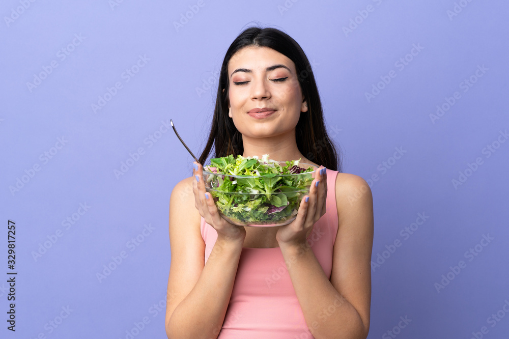 Young woman with salad over isolated purple background