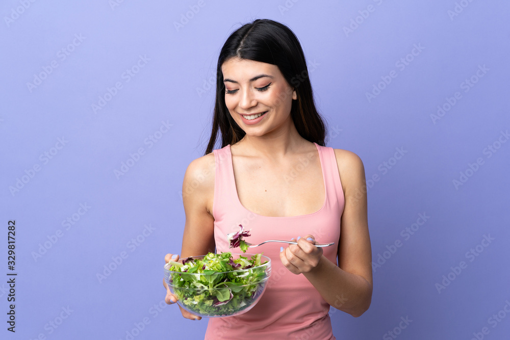 Young woman with salad over isolated purple background Young woman with salad over isolated purple background