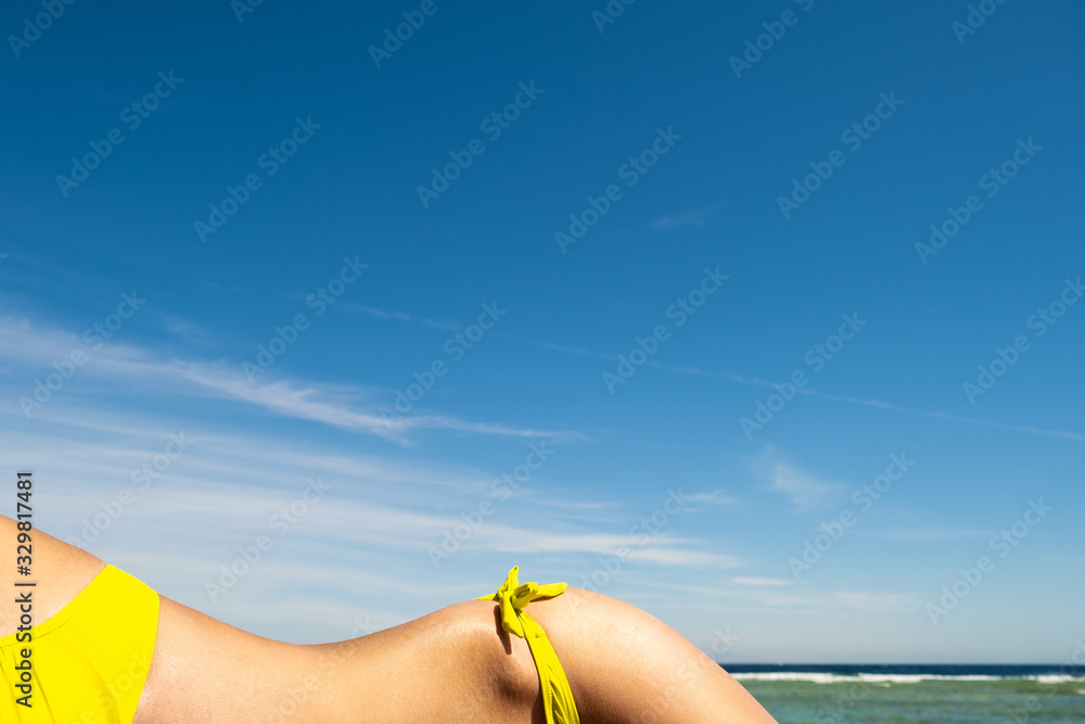 Fototapeta premium Close up of young woman hip and shoulder laying on beach chair at sea shore sunbathing.