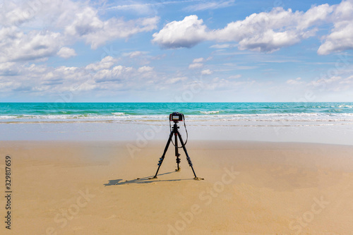 Digital professional camera stand on tripod photographing sea.