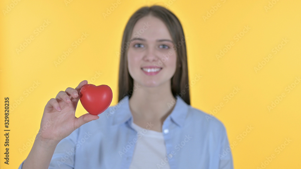 Young Woman holding Red Heart Shape, Yellow Background Young Woman holding Red Heart Shape, Yellow Background