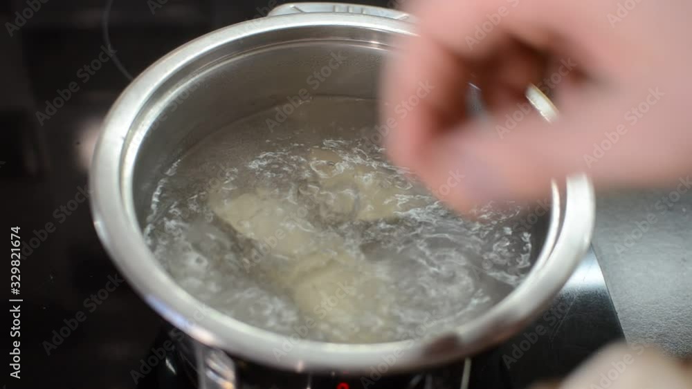 Dumplings are boiled in boiling water in a pan on an induction stove. Dumplings are boiled in boiling water in a pan on an induction stove.