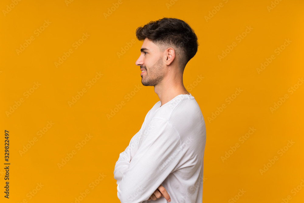 Young man over isolated orange background in lateral position Young man over isolated orange background in lateral position