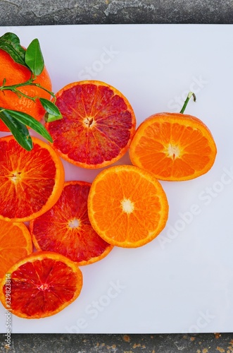 Fototapeta Naklejka Na Ścianę i Meble -  Platter of orange and mandarosa red clementines cut in half on a white platter