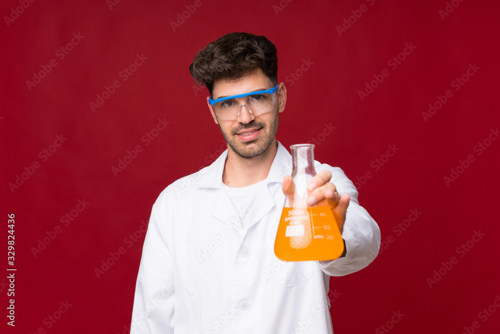 Young man over isolated background with a scientific test tube Young man over isolated background with a scientific test tube