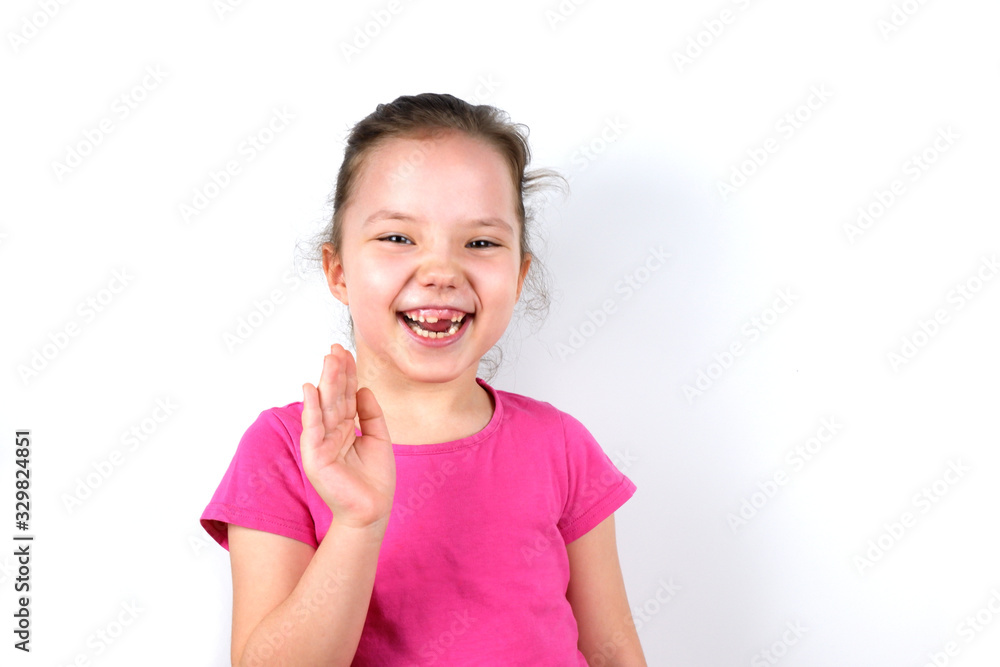 Laughing six years old little beautiful girl with greeting gesture raised hand on white background. Childhood, goodwill, greeting, kindness, welcome, hospitality, goods and services for children Laughing six years old little beautiful girl with greeting gesture raised hand on white background. Childhood, goodwill, greeting, kindness, welcome, hospitality, goods and services for children