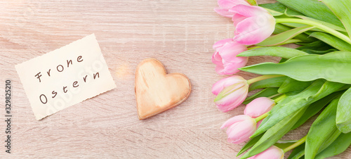 Rosarote Tulpen auf einem Holztisch mit Osterkarte "Frohe Ostern"