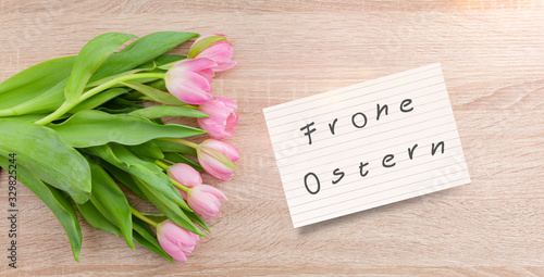 Rosarote Tulpen auf einem Holztisch mit Osterkarte "Frohe Ostern"
