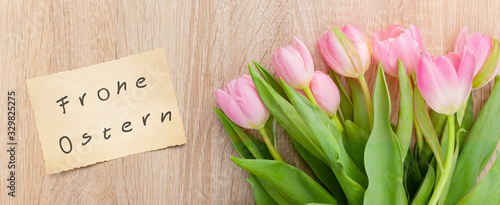 Rosarote Tulpen auf einem Holztisch mit Osterkarte "Frohe Ostern"