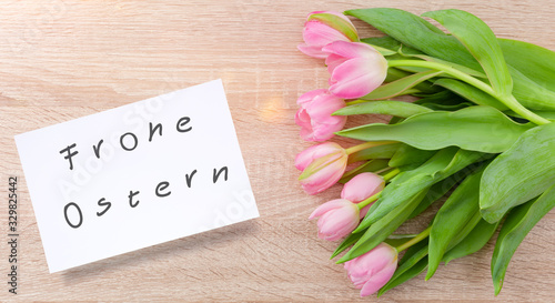 Rosarote Tulpen auf einem Holztisch mit Osterkarte "Frohe Ostern"