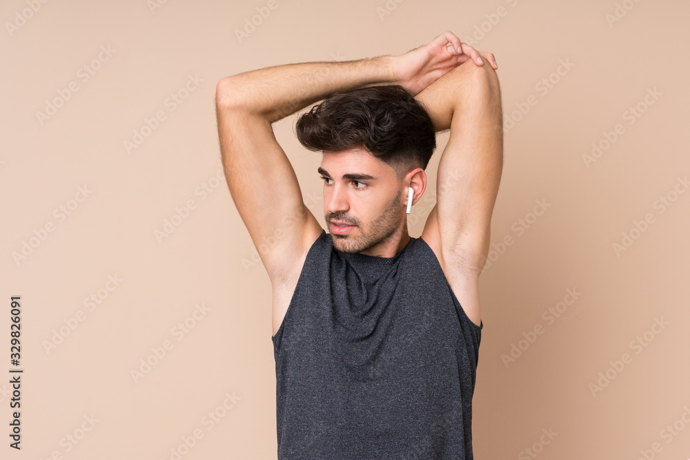 Young sport man over isolated background stretching arm Young sport man over isolated background stretching arm
