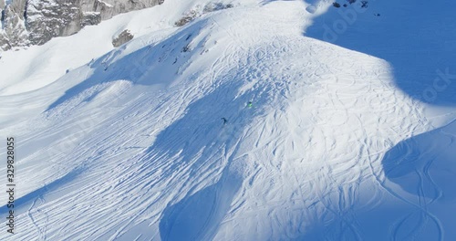 Two skiers going downhill off-piste in the Swiss Alps. Two people skiing. Captured by drone.
