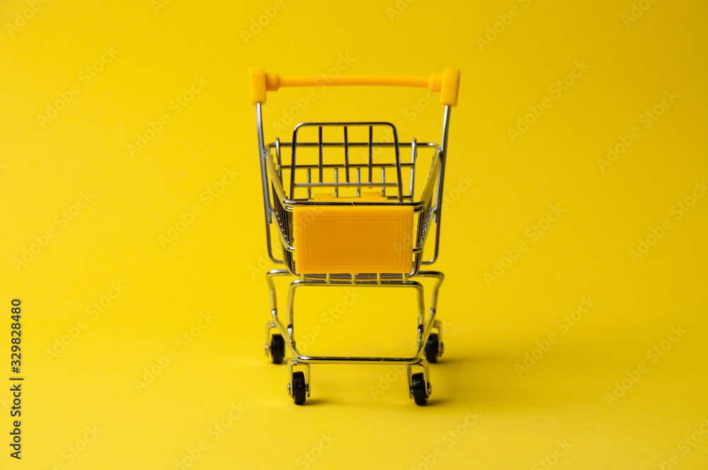 Cart for shopping on a yellow background. Supermarket food price concept, holiday discounts Cart for shopping on a yellow background. Supermarket food price concept, holiday discounts